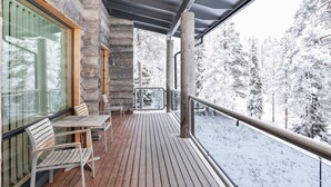 Une terrasse en bois dotée d’une balustrade en verre, offrant une vue sur un paysage enneigé.