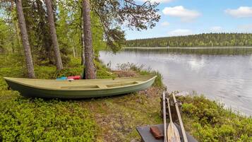 A canoe tied to a tree by a calm lake with a forest in the background.