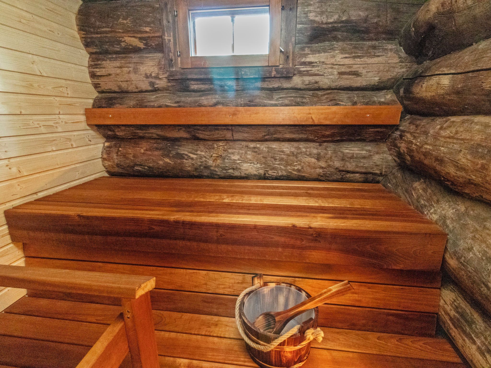 A log cabin interior with a wooden bench, a small window, and a rustic ambiance.