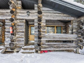 Une cabane en rondins avec une porte en bois, une fenêtre avec des rideaux et un extincteur fixé au mur.