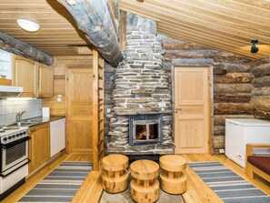 A cozy cabin interior with a stone fireplace, wooden cabinets, and a dining area with stools.