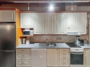 A kitchen with white cabinets, a microwave, a sink, and a stove.