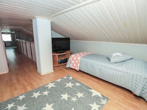 A bedroom with a bed, a television, and a camera on a shelf.
