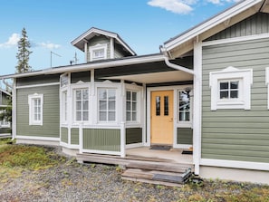 A two-story house with a porch, a front door, and a small step leading to the entrance.