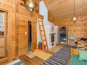 A wooden cabin interior with a loft bedroom, a fireplace, a ladder, and a cozy seating area. - Tallukka by Interhome (Pertunmaa)