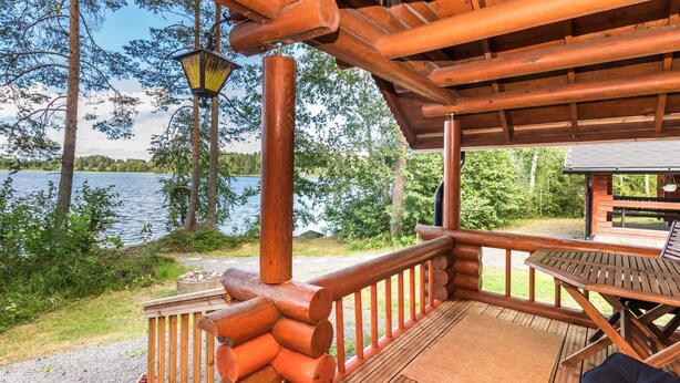 A wooden deck with a table and chairs, overlooking a lake.