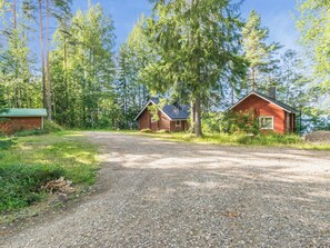 A gravel driveway leading to two log cabins surrounded by dense forest. - Tallukka by Interhome (Pertunmaa)