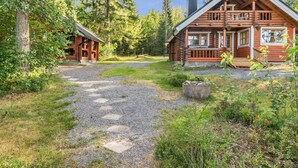 A rustic cabin with a stone pathway leading to it, surrounded by dense forest.