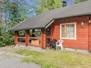 A wooden cabin with a porch, a window, and a chair. - Tallukka by Interhome (Pertunmaa)