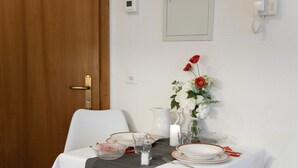 Een eettafel gedekt met borden, glazen, een karaf en een vaas met bloemen.