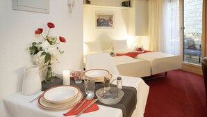 Een hotelkamer met een eethoek gedekt voor twee personen, een bed en uitzicht op het omliggende landschap.