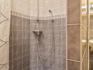 A shower with a handheld showerhead and a fixed showerhead, both mounted on a tiled wall. - Kaltiotievantie 2 mökki 3 by Interhome (Ylläsjärvi)