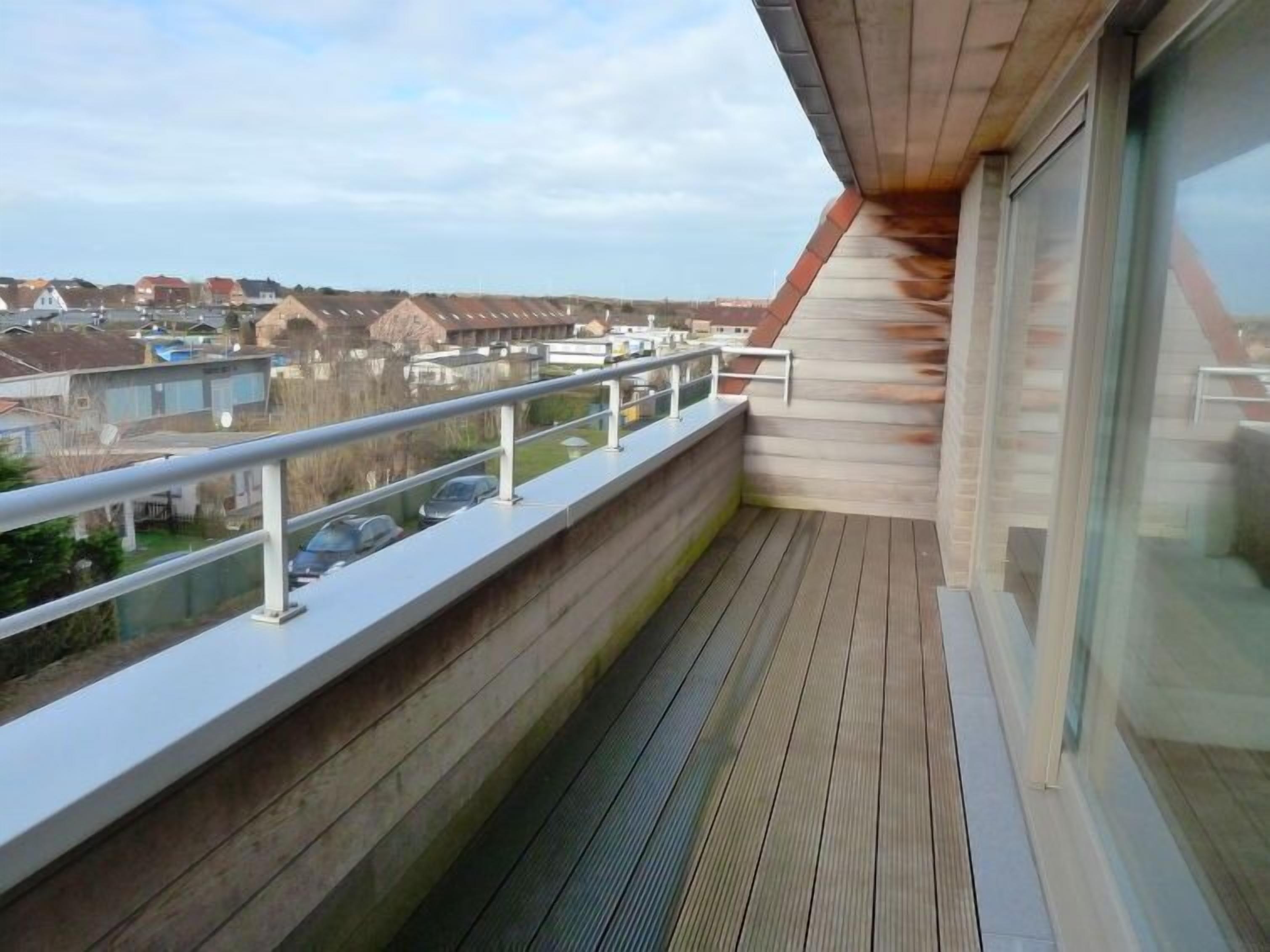 A balcony with a view of houses and a clear sky.