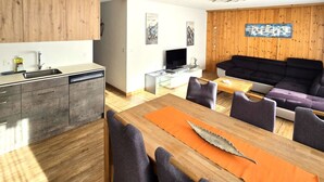 A modern living space with a kitchen, dining area, and a seating area with a sofa and chairs. - Ferienhaus Adonis by Interhome (Saas-Grund)