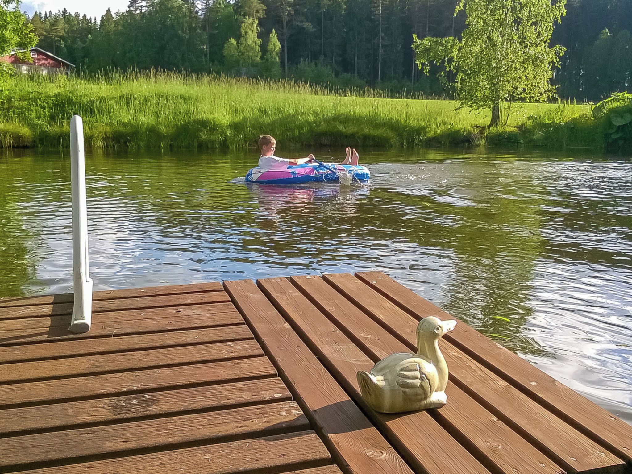 A wooden dock with a duck sculpture and a fishing rod.