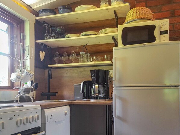 Une cuisine compacte équipée d’un réfrigérateur, d’une machine à café et d’un grille-pain.