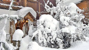 Een gebouw bedekt met sneeuw, met een houten gevel en een duidelijke ingang.