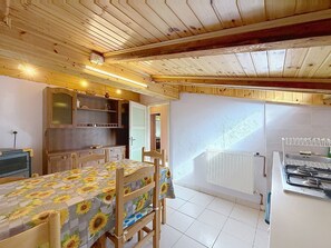 A kitchen with a dining area, wooden ceiling, and a radiator. - La Busa by Interhome (Alleghe)