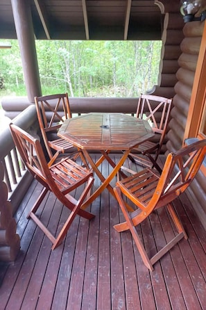 A wooden deck with a round table and chairs, surrounded by a wooden railing. - Ranta-koivu by Interhome (Kinnula)