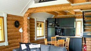 Ein gemütliches Holzhaus-Interieur mit einem modernen Wohnbereich, einem Esstisch und einer Küche.