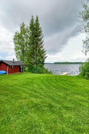 A grassy yard with a red building and a large tree.