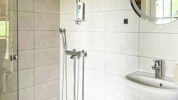 A modern bathroom with a glass shower enclosure, a wall-mounted sink, and a ceiling light.