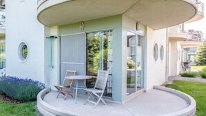 Un bâtiment moderne doté d’un balcon circulaire, d’un espace extérieur aménagé pour s’asseoir et d’une entrée avec une porte en verre.