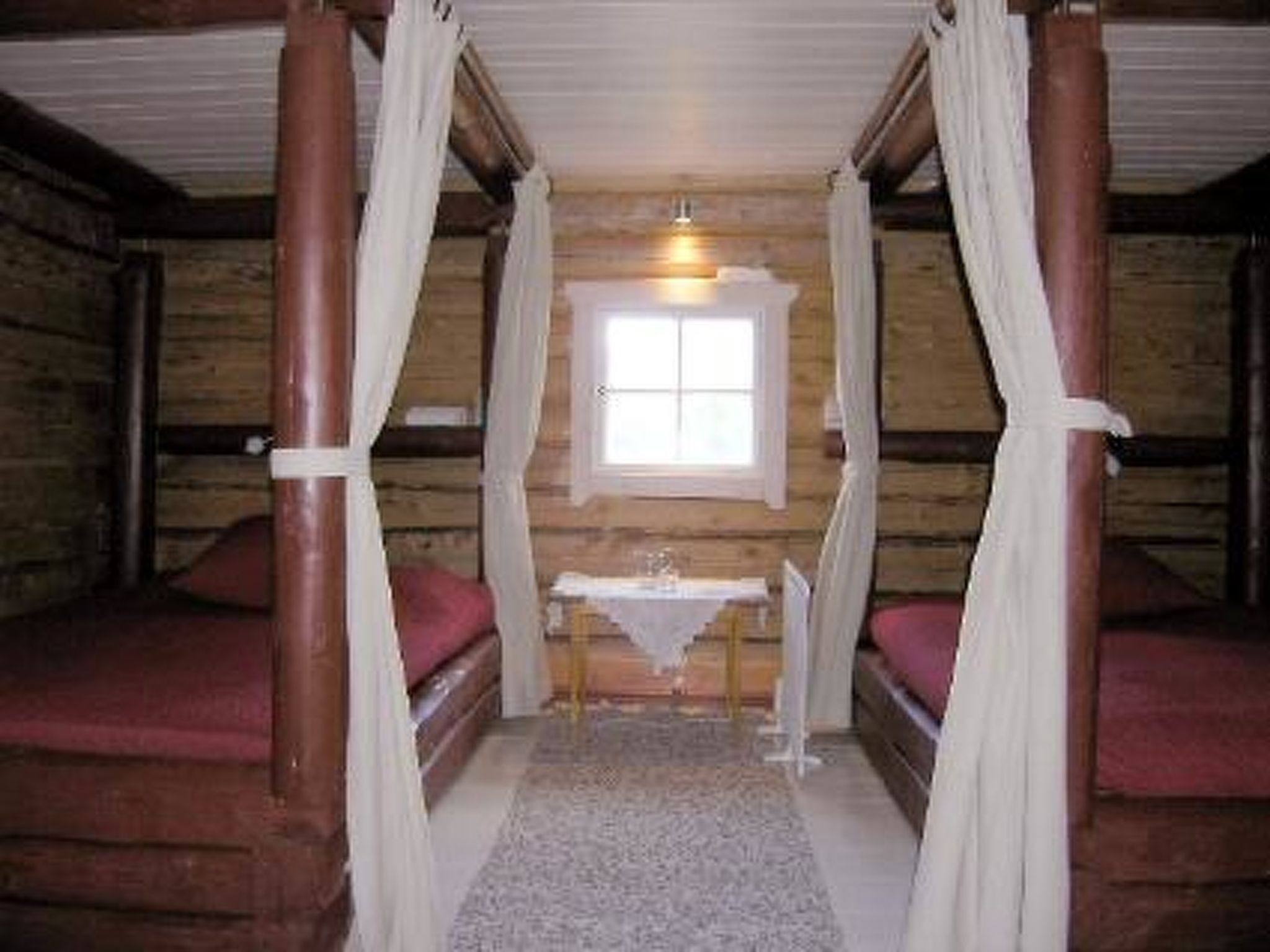 Een kamer met twee bedden, een tafeltje en een raam.