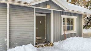 En liten, envåningsbyggnad med en grå fasad och en vit dörr.