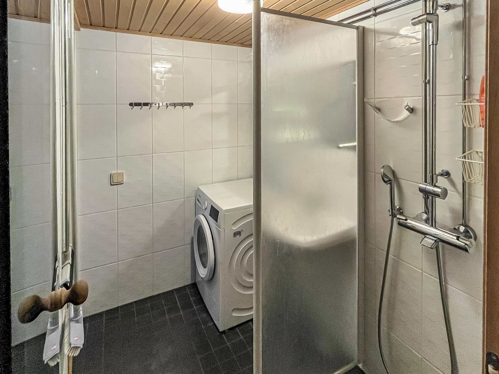 Moderni kylpyhuone, jossa on suihku, wc ja pesukone.