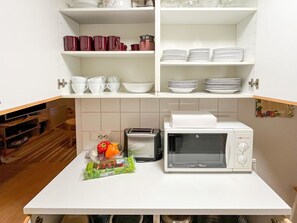 Een koelkast, een magnetron, een vaatwasser, kookgerei, borden en bestek