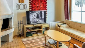 Ett mysigt vardagsrum med en öppen spis, en tv, en soffa och ett litet bord.