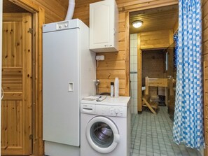 Pieni ja käytännöllinen pyykinhuone, jossa on pyykinpesukone, kuivausrumpu ja pieni kaappi.