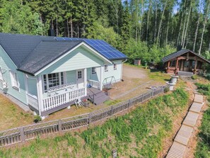 A light blue cabin with solar panels, a porch, and a small adjacent wooden structure. - Koivurinne by Interhome (Punkaharju)