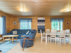 A cozy cabin interior with a sofa, chairs, a dining table, and a fireplace.