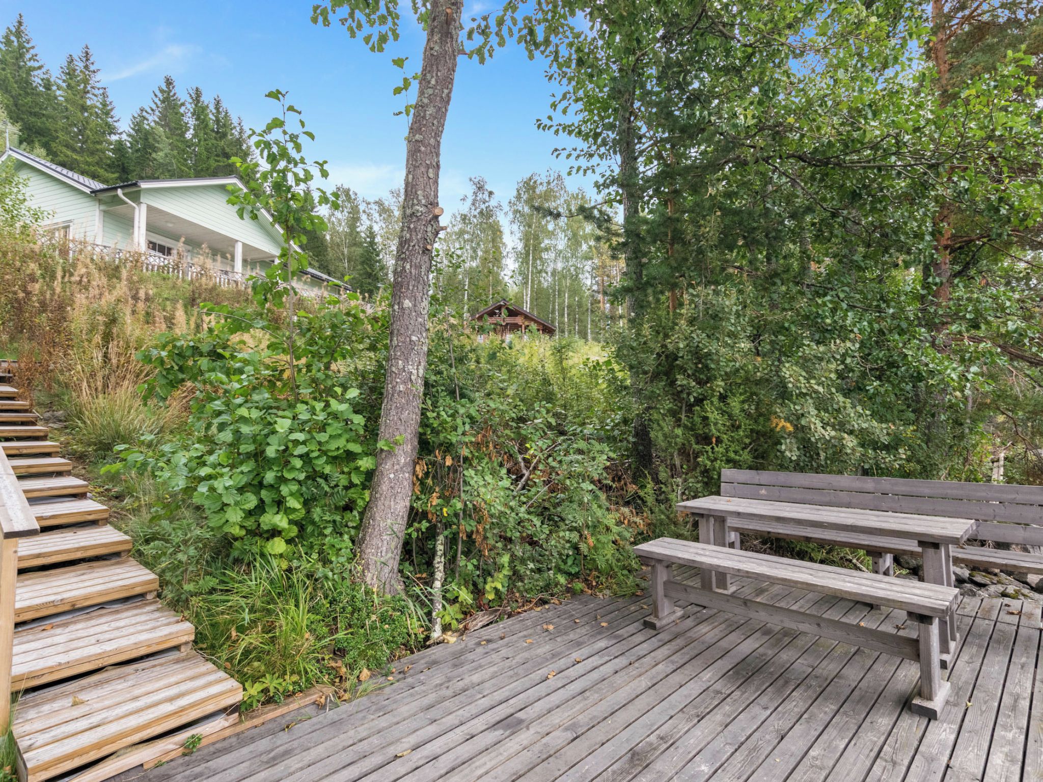 A wooden deck with a picnic table and steps leading to a building.