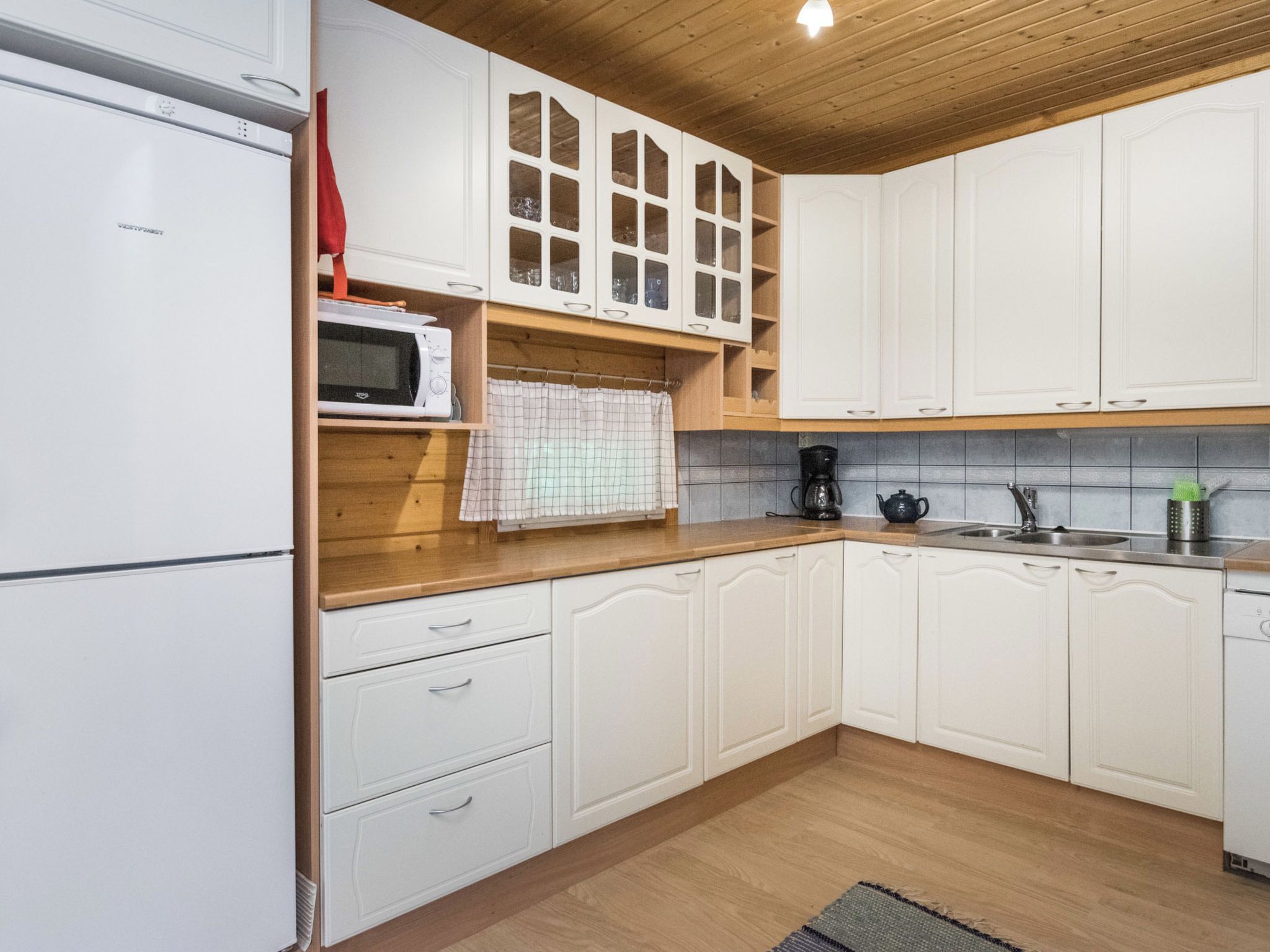 A kitchen with white cabinets, a microwave, a coffee maker, and a sink.