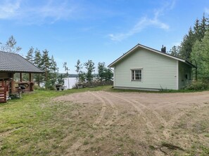 A rustic cabin with a dirt driveway, surrounded by trees and a clear sky. - Koivurinne by Interhome (Punkaharju)