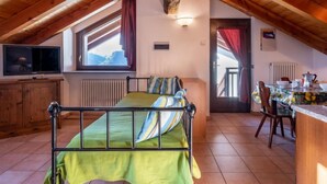 A cozy attic bedroom with a bed, a TV, a dining area, and a view of the mountains. - Grand Sarriod by Interhome (St Nicolas)