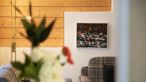 Una habitación con pared de madera, una obra enmarcada que muestra una escena abstracta y colorida, y un sofá de cuadros.