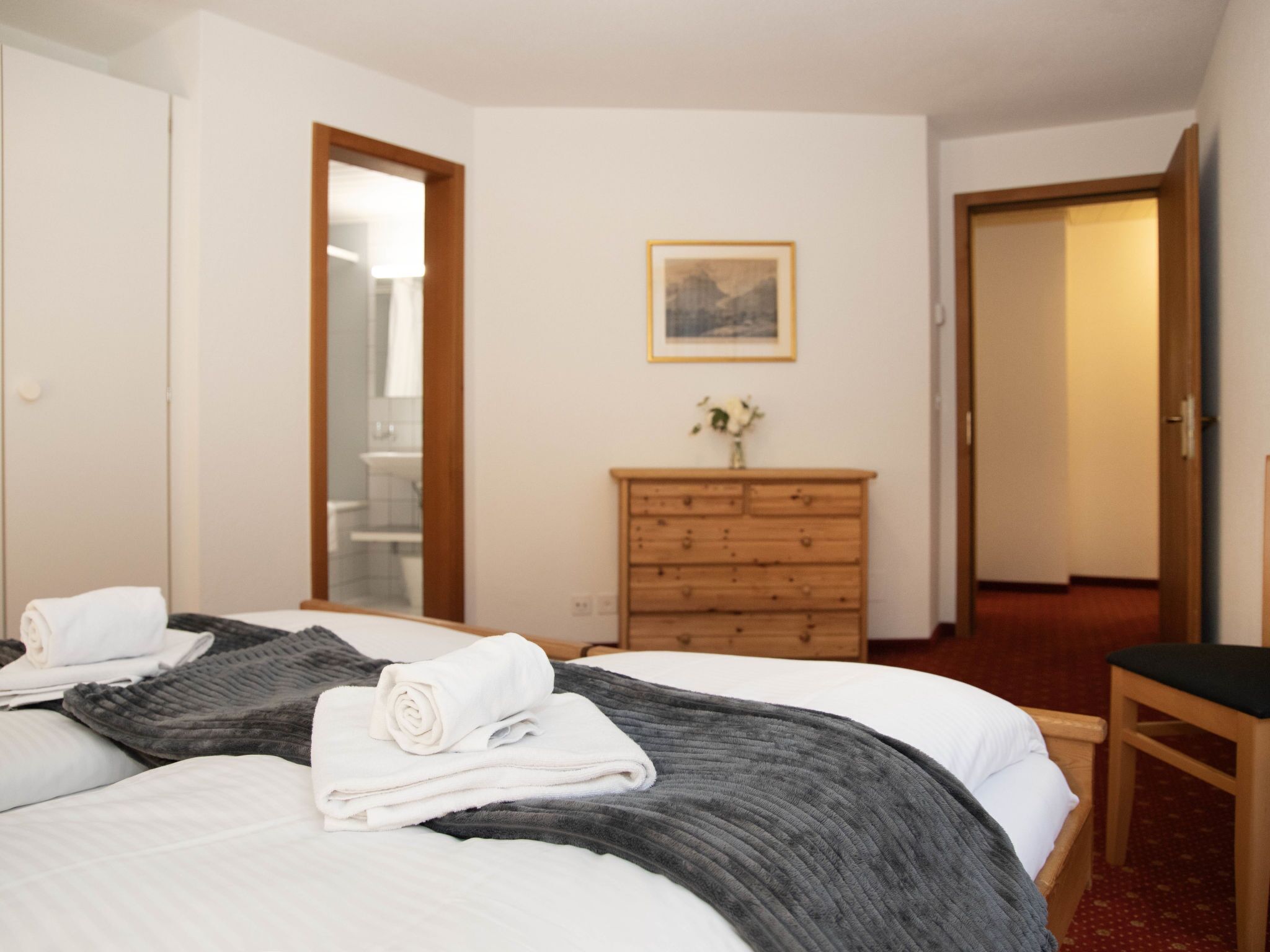 Ein Hotelzimmer mit einem Bett, einer Holzkommode, einem Spiegel und einem gerahmten Bild an der Wand.