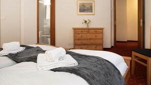 Una habitación de hotel con una cama, un aparador de madera, un espejo y un cuadro en la pared.