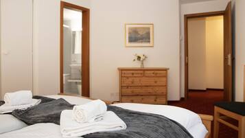 Ein Hotelzimmer mit einem Bett, einer Holzkommode, einem Spiegel und einem gerahmten Bild an der Wand.