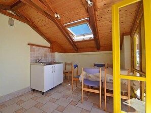 A compact kitchen with a tiled backsplash, a white refrigerator, and a skylight. There are two wooden chairs and a small table.