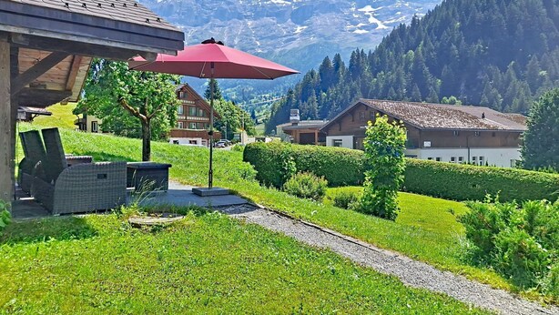 A chalet with a patio, a red umbrella, and a mountain view. - Chalet Schwendihus by Interhome (Grindelwald)