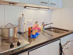 Une cuisine équipée d’une cuisinière Bosch, d’un évier et d’un plan de travail sur lequel se trouvent divers objets.