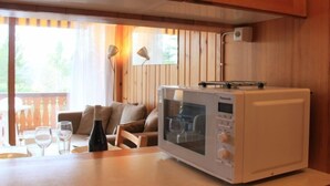 A compact kitchen with a built-in microwave, a wooden countertop, and a dining area with a table and chairs.