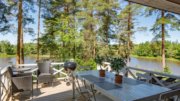 A deck with a table and chairs, overlooking a lake surrounded by trees. - Kivitasku by Interhome (Somero)