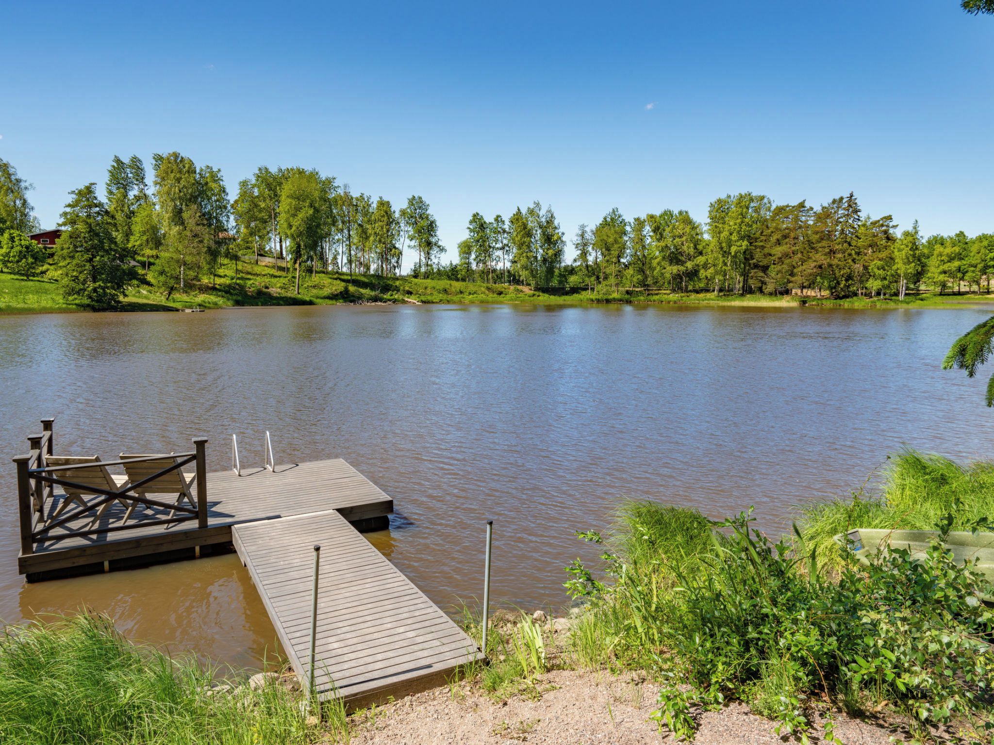 A calm lake with a wooden dock and a grassy bank.