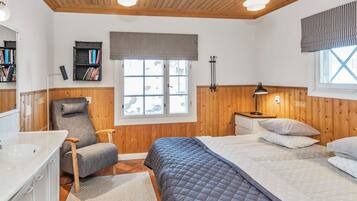 Une chambre à coucher comprenant un lit, une chaise, un bureau, une fenêtre et un lambris en bois.